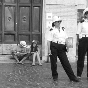 zwei italienische Polizistinnen stehen vor einer Kirchentür. Im Hintergrund auf der Stufe Touristen mit Kamera